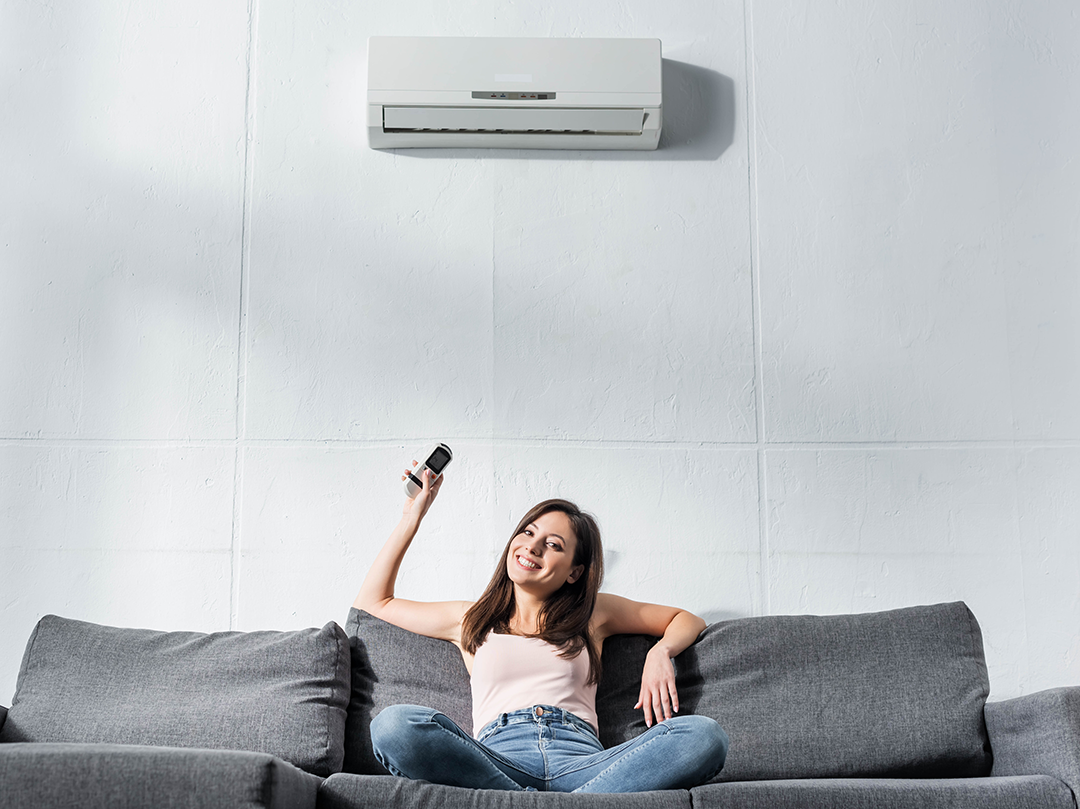 attractive-and-smiling-woman-switching-on-air-cond-2024-11-18-20-42-02-utc How Ductless Heat Pumps Work for Southern Illinois Homes